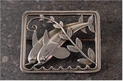 A rectangular Georg Jensen brooch (design number 251) depeciting a pair of dolphins
        designed by Arno Malinowski.