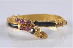 A 19th century gold ruby, tortoiseshell and star-sapphire mounted hinged bangle. Estimate £800-£1,200.