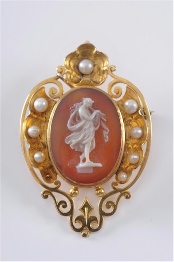 An oval cornelian agate and cultured seed pearl cameo brooch/pendant within a frame
        of scroll pierced design, 51mm overall. Estimate £700-£900.