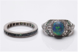 An early 20th Century black opal, emeral and diamond cluster ring with an emerald eternity ring in channel setting. Realised £2,600. (FS15/148).