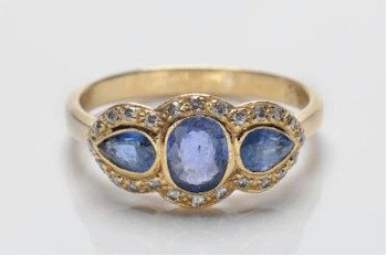 A sapphire and diamond mounted triple cluster ring with central oval sapphire between pear-shaped stones within a surround of small diamonds in 19th century style (FS19/157).