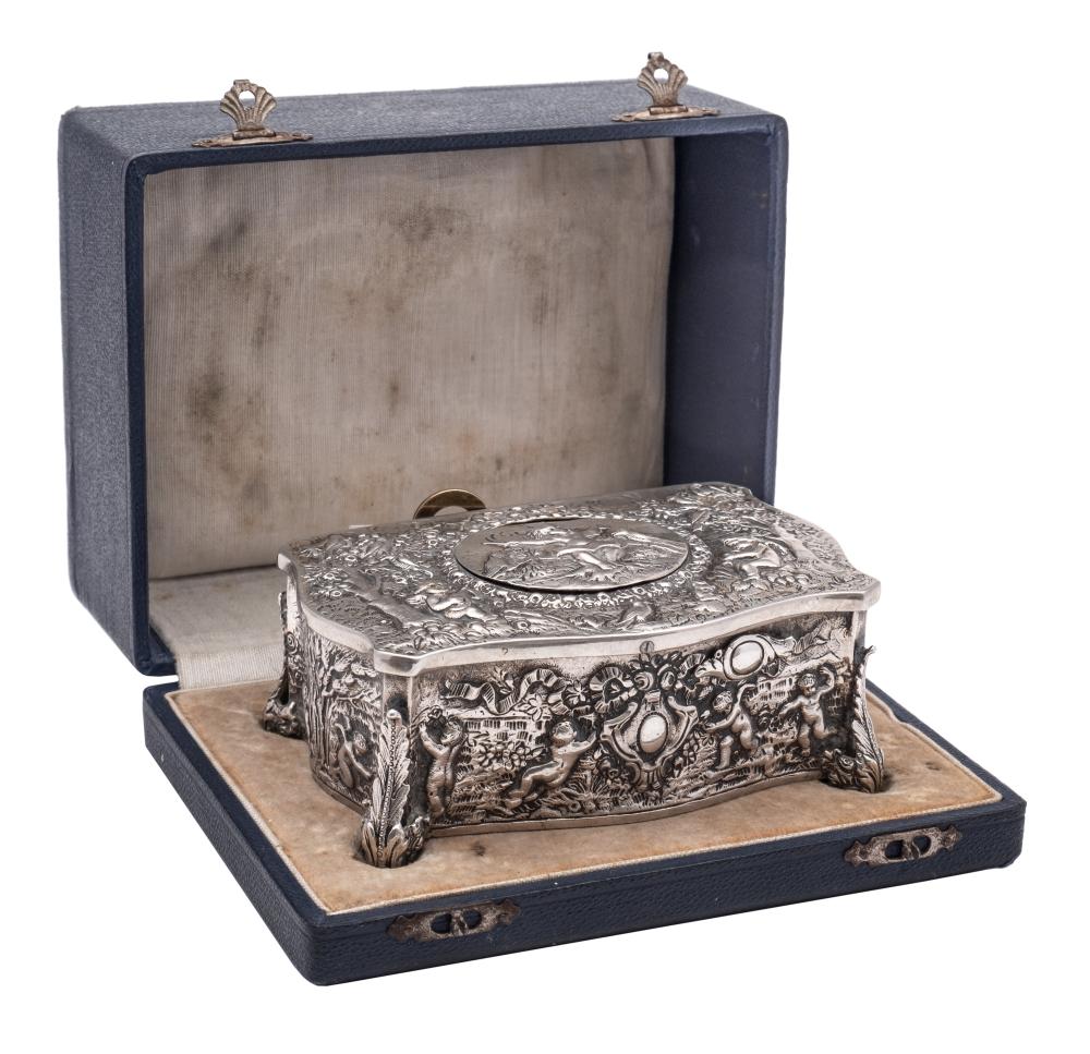 A Swiss Silver Plated Automaton Musical Box Of Serpentine Outline Decorated With Putti In Forest